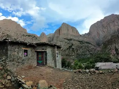 a small building with a red door in the mountains at Gîte Baraka Taghia in Taghia