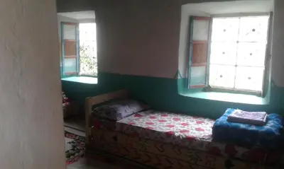 a small bedroom with a bed and two windows at Gîte Baraka Taghia in Taghia