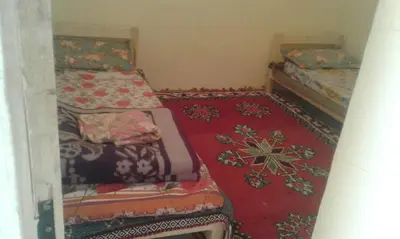 two beds in a small room with red carpet at Gîte Baraka Taghia in Taghia