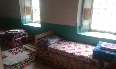 a small bedroom with a bed and two windows at Gîte Baraka Taghia in Taghia