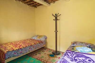 a room with two beds and a pole in the corner at Gîte Baraka Taghia in Taghia