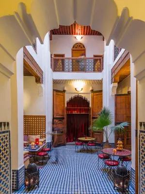 a lobby with tables and chairs and a balcony at Riyad Al Atik in Fès