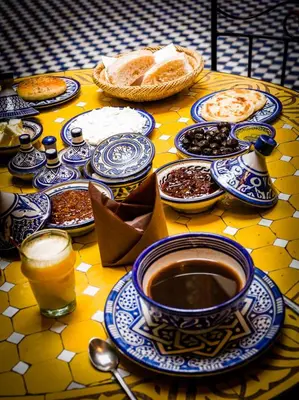 a table with blue and white plates and cups of coffee at Riyad Al Atik in Fès