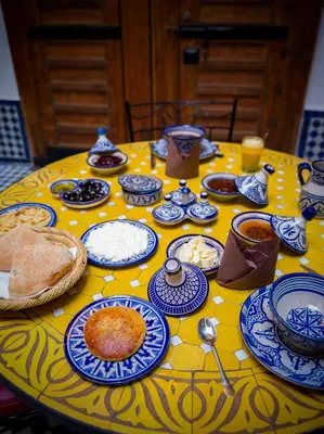 a yellow table with blue and white dishes on it at Riyad Al Atik in Fès
