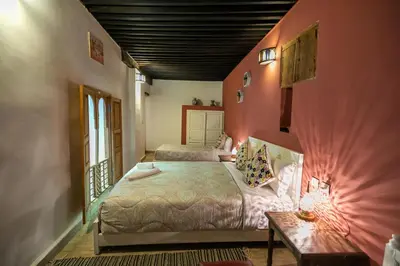 a bedroom with two beds in a room with pink walls at Riad Hidaya in Fès