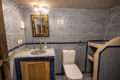 a blue tiled bathroom with a toilet and a sink at Riad Hidaya in Fès