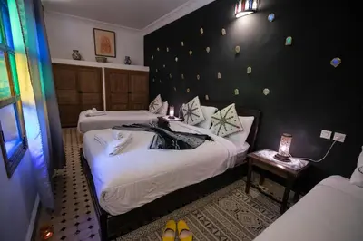 two beds in a room with a black wall at Riad Hidaya in Fès