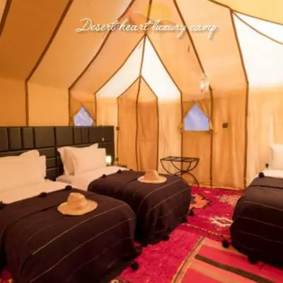 two beds in a tent with hats on them at Desert Heart Luxury Camp in Merzouga