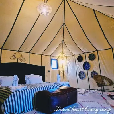 a bedroom with a tent with a bed and a chair at Desert Heart Luxury Camp in Merzouga