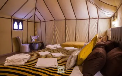 a person laying on a bed in a tent at Luxury oasis camp in Merzouga
