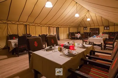 a dining tent with tables and chairs in it at Luxury oasis camp in Merzouga