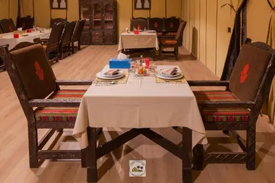 a dining room table with a white table cloth and chairs at Luxury oasis camp in Merzouga