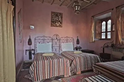 two beds in a bedroom with pink walls at Sawadi Ecolodge in Skoura