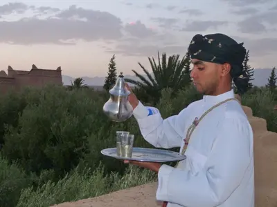 a man holding a silver tea kettle on a tray at Sawadi Ecolodge in Skoura