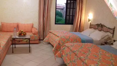 a hotel room with two beds and a table with fruit at Belere Arfoud in Erfoud