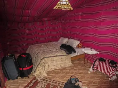 a bedroom with a bed with a purple wall at Visit Morocco Sahara Camp in Merzouga