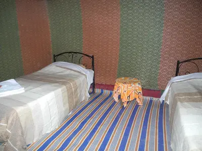a bedroom with two beds and a table on the floor at Visit Morocco Sahara Camp in Merzouga