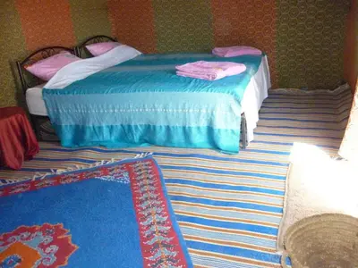 a bedroom with two beds and a rug at Visit Morocco Sahara Camp in Merzouga