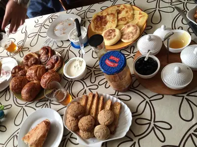 a table topped with plates of bread and pastries at Visit Morocco Sahara Camp in Merzouga