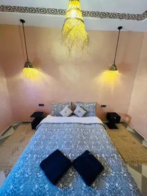 a bedroom with a bed with blue sheets and lights at Hiking Nomads Guesthouse in Tamellalt