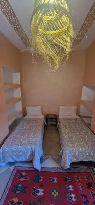 a bedroom with two beds and a chandelier at Hiking Nomads Guesthouse in Tamellalt