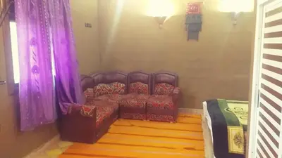 a living room with a couch with purple curtains at Auberge Camping BOUGAFER Tamtetoucht in Tamtetoucht