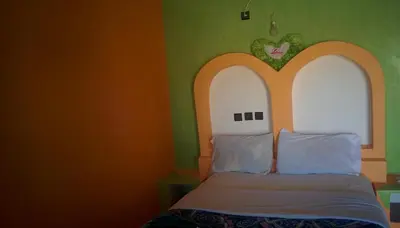 a bedroom with a bed with an orange and green wall at Auberge Camping BOUGAFER Tamtetoucht in Tamtetoucht