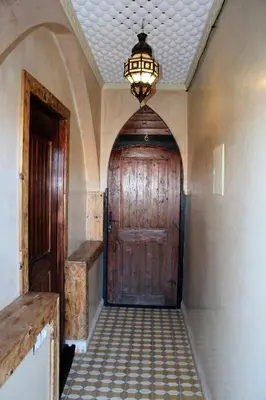 a hallway with a large wooden door and a chandelier at Dar Diafa Kaltom in Ouzoud