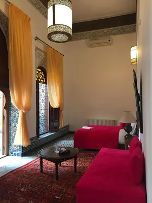 a living room with a red couch and a red bed at Riad jasmins & Spa in Fès