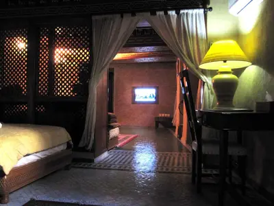 a bedroom with a bed and a desk with a lamp at Riad Jaouhara in Fès