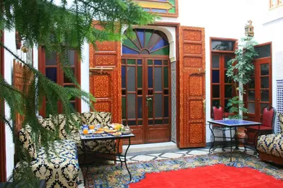 an entrance to a house with a red door and a table at Riad Lalla Fatima in Fès