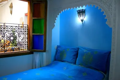 a blue bedroom with a bed and a window at Riad Lalla Fatima in Fès
