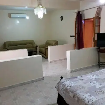 a living room with a bed and a couch and chairs at Oasispalmares in Er Rachidia