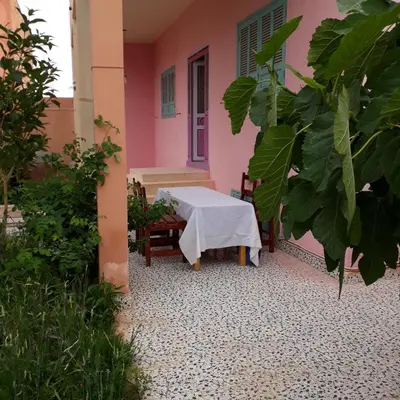 a table in the courtyard of a pink house at Oasispalmares in Er Rachidia