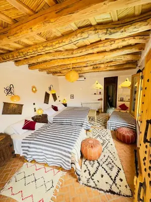 two beds in a room with wooden ceilings at Dar Ahlam Dades Hotel in Aït Ouaddar