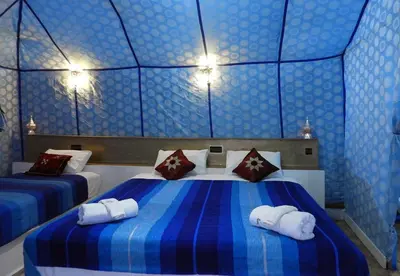 a blue room with two beds with towels on them at Luxury Sahara Dream Camp in Merzouga