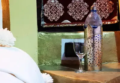 a bottle and a wine glass on a table at Luxury Sahara Dream Camp in Merzouga
