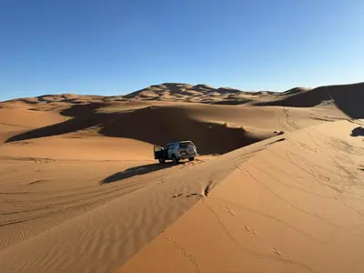 a truck parked on top of a sand dune at Maison Merzouga Guest House in Merzouga