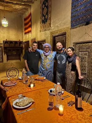 a group of people standing around a table at Maison Merzouga Guest House in Merzouga
