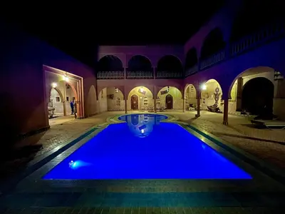 a swimming pool in a courtyard at night at Maison Merzouga Guest House in Merzouga