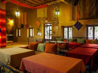 a room with tables and a couch in a room at Maison Merzouga Guest House in Merzouga
