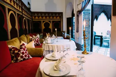 a restaurant with two tables with wine glasses on them at Riad Maison Bleue and Spa in Fès