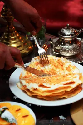 a person cutting a stack of pancakes with a fork and knife at Riad Maison Bleue and Spa in Fès