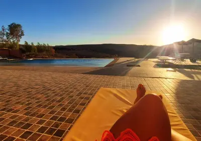 a person laying on a towel next to a body of water at Kasbah Zitoune in Ouarzazate