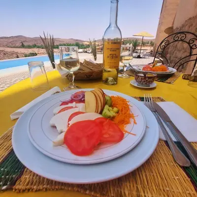 a plate of food on a table with a bottle of wine at Kasbah Zitoune in Ouarzazate