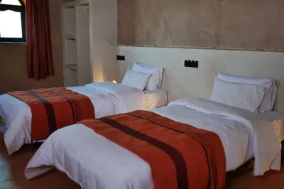 two beds in a hotel room with white and orange sheets at Kasbah Zitoune in Ouarzazate