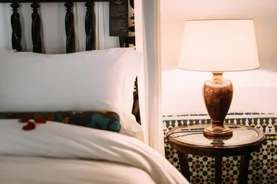 a lamp on a table next to a bed at La Maison Bleue Batha in Fès