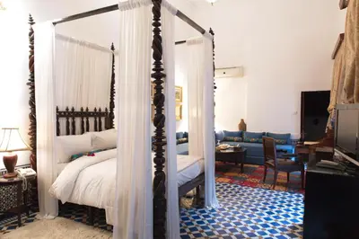 a bedroom with a canopy bed and a living room at La Maison Bleue Batha in Fès