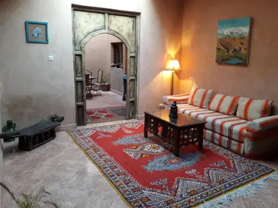 a living room with a couch and a red rug at Dar Bilal in Aït Ben Haddou