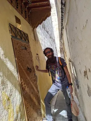 a man is standing in an alley near a door at Dar nadaa in Fès
